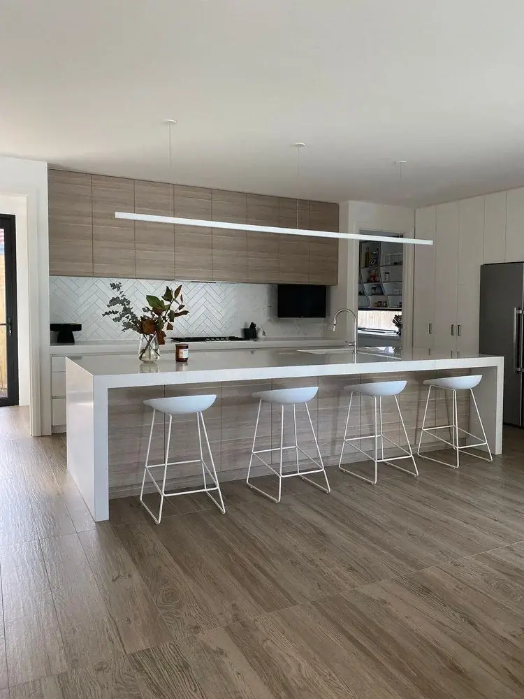 White kitchen with stone island, bar stools and timber flooring