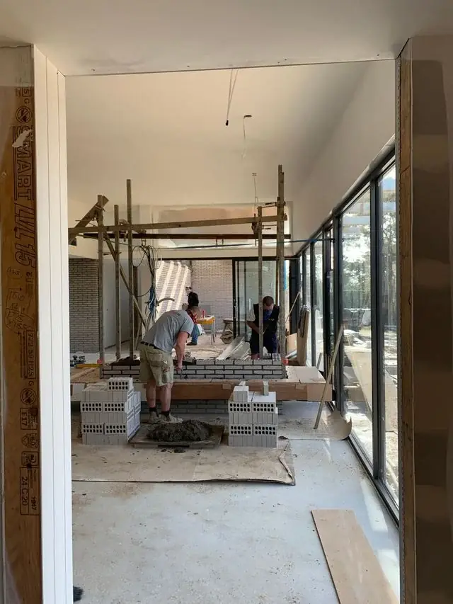Interior renovation in progress beside full-height glass doors