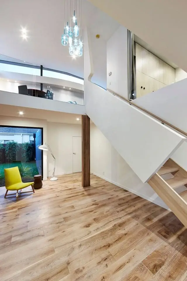 White staircase beside timber flooring and a double-height living space